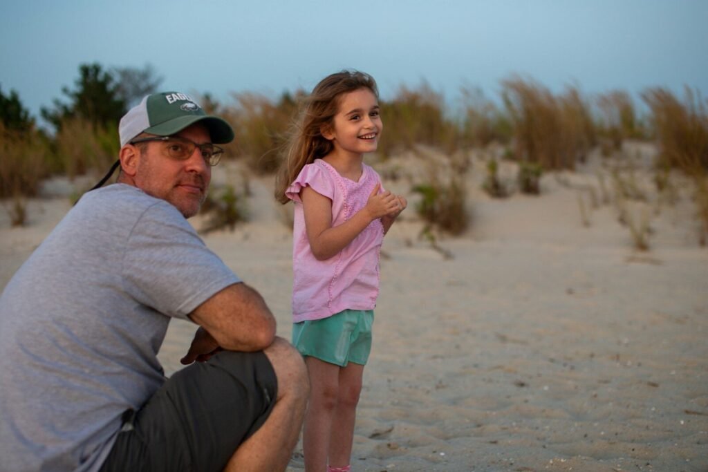 Man and girl on a sandy beach with grass